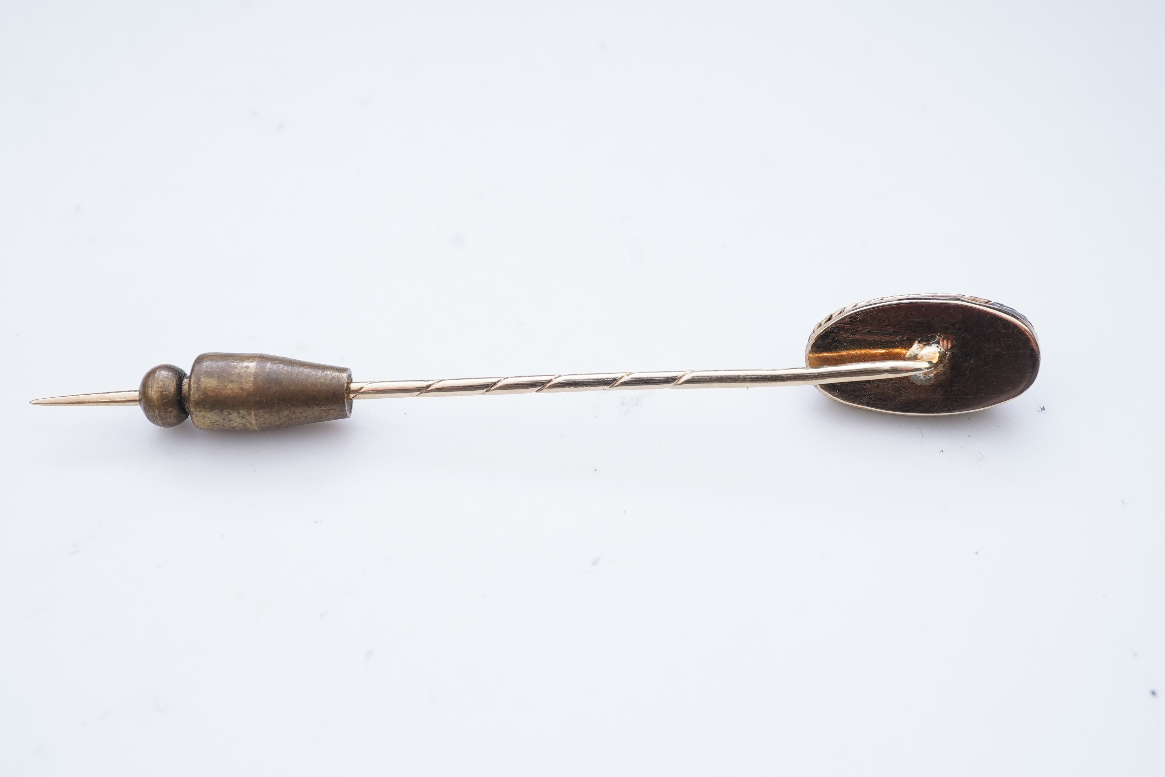 A collection of six stick pins, comprising: three gold stick pins, one set with a hardstone cameo, Austrian assay marks; a gold stick pin with a faceted edge; and a gold stick pin of Masonic design, stamped 9CT, combined